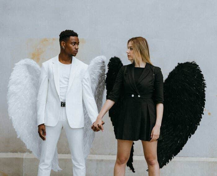 Two people dressed as contrasting angels, one in white and one in black, symbolizing the balance between bad credit and improving credit scores with credit cards