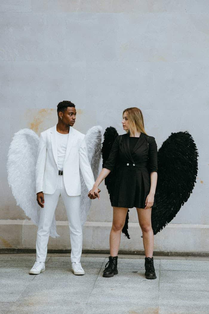 Two people dressed as contrasting angels, one in white and one in black, symbolizing the balance between bad credit and improving credit scores with credit cards