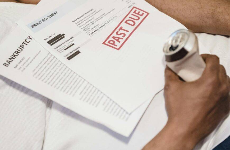 A man lying down with past due letters and bills on his chest, symbolizing the impact of bankruptcy and financial distress in the UK since 2000