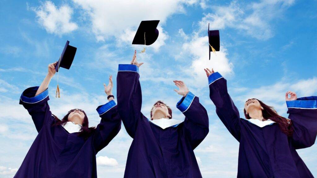 Students in graduation gowns throwing caps in the air, symbolizing financial independence and credit-building opportunities for students