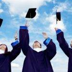 Students in graduation gowns throwing caps in the air, symbolizing financial independence and credit-building opportunities for students