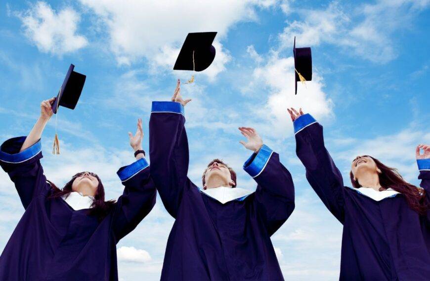 Students in graduation gowns throwing caps in the air, symbolizing financial independence and credit-building opportunities for students