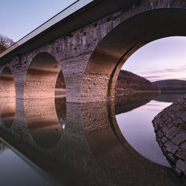 A bridge with multiple arches reflected in the water, symbolizing the concept of bridging loans and the BRRR (Buy, Rehab, Rent, Refinance) method in real estate investment