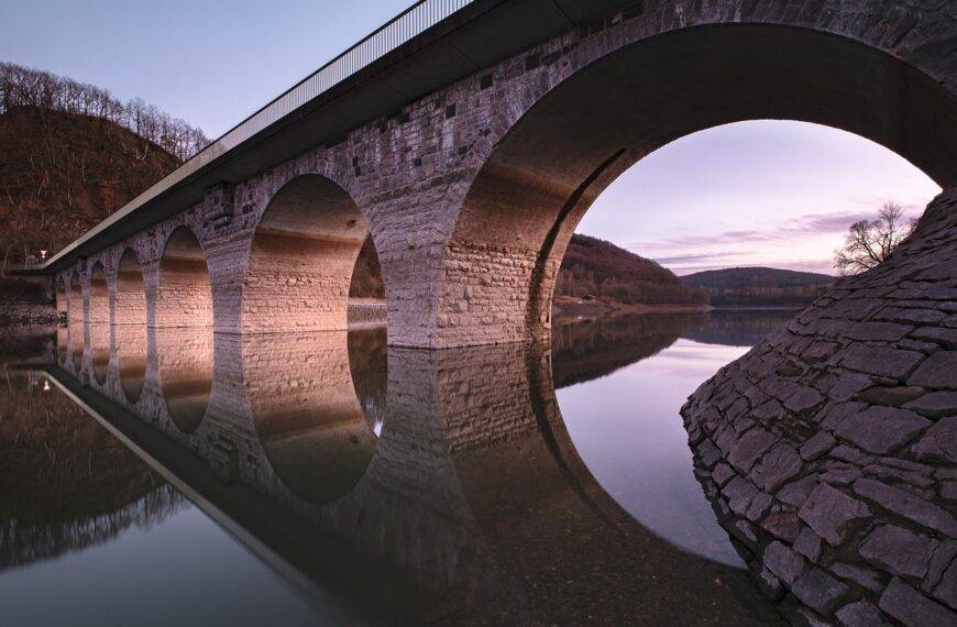 A bridge with multiple arches reflected in the water, symbolizing the concept of bridging loans and the BRRR (Buy, Rehab, Rent, Refinance) method in real estate investment