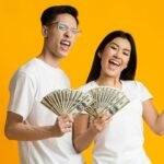 Happy couple holding cash, symbolizing the success of building and sticking to a budget effectively.