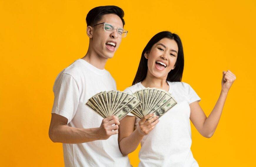 Happy couple holding cash, symbolizing the success of building and sticking to a budget effectively.