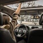 Driver inside a car with hand reaching out the sunroof, symbolizing early termination options for car finance in the UK including PCP, HP, and leasing