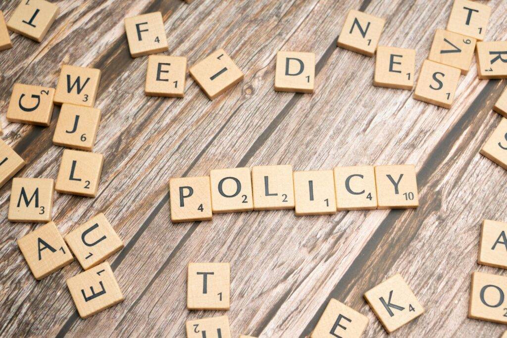 The word "POLICY" spelled out with letter tiles on a wooden surface, symbolizing new regulations on card services and the future of payments in the UK