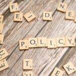 The word "POLICY" spelled out with letter tiles on a wooden surface, symbolizing new regulations on card services and the future of payments in the UK