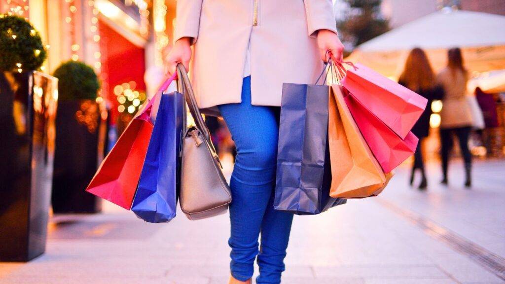 Person carrying multiple shopping bags, illustrating how habits like shopping can influence financial decisions