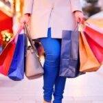 Person carrying multiple shopping bags, illustrating how habits like shopping can influence financial decisions