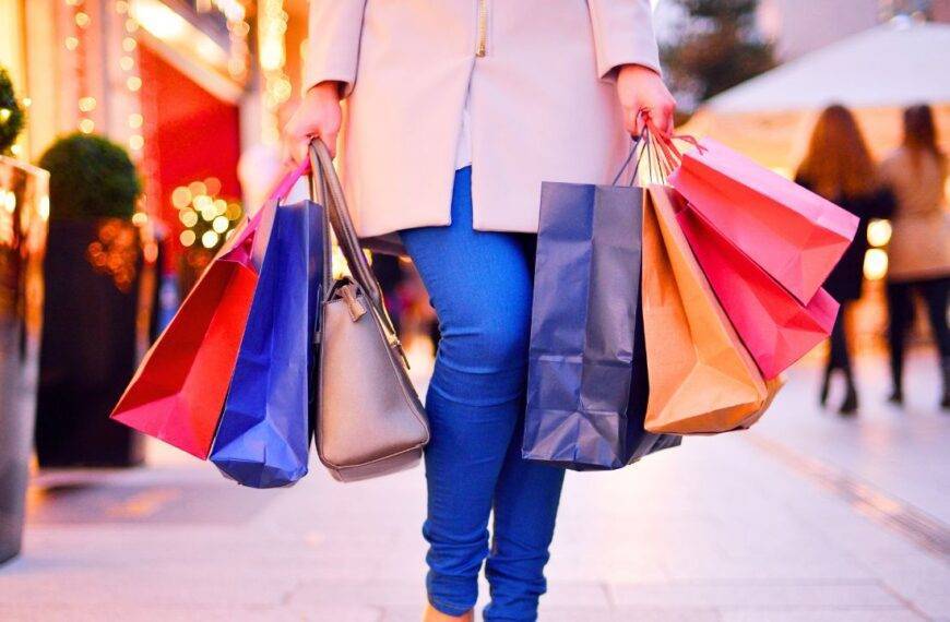 Person carrying multiple shopping bags, illustrating how habits like shopping can influence financial decisions