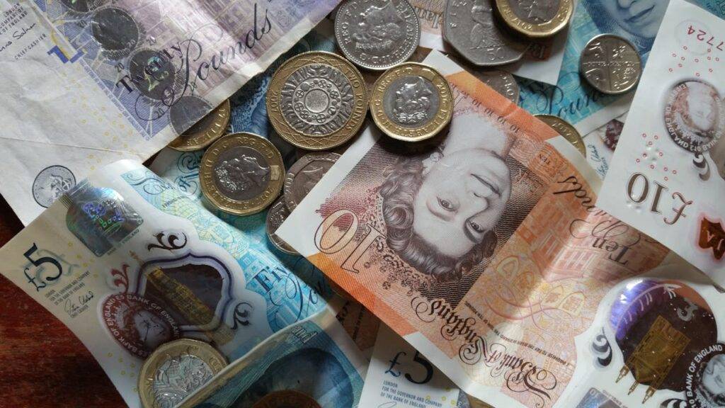 Close-up of British currency notes and coins, representing the financial comparison between overdrafts and credit cards in the UK