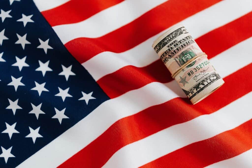 Rolled US dollar bills on an American flag, representing a comparative analysis of overdrafts versus credit cards for consumers in the US and Canada