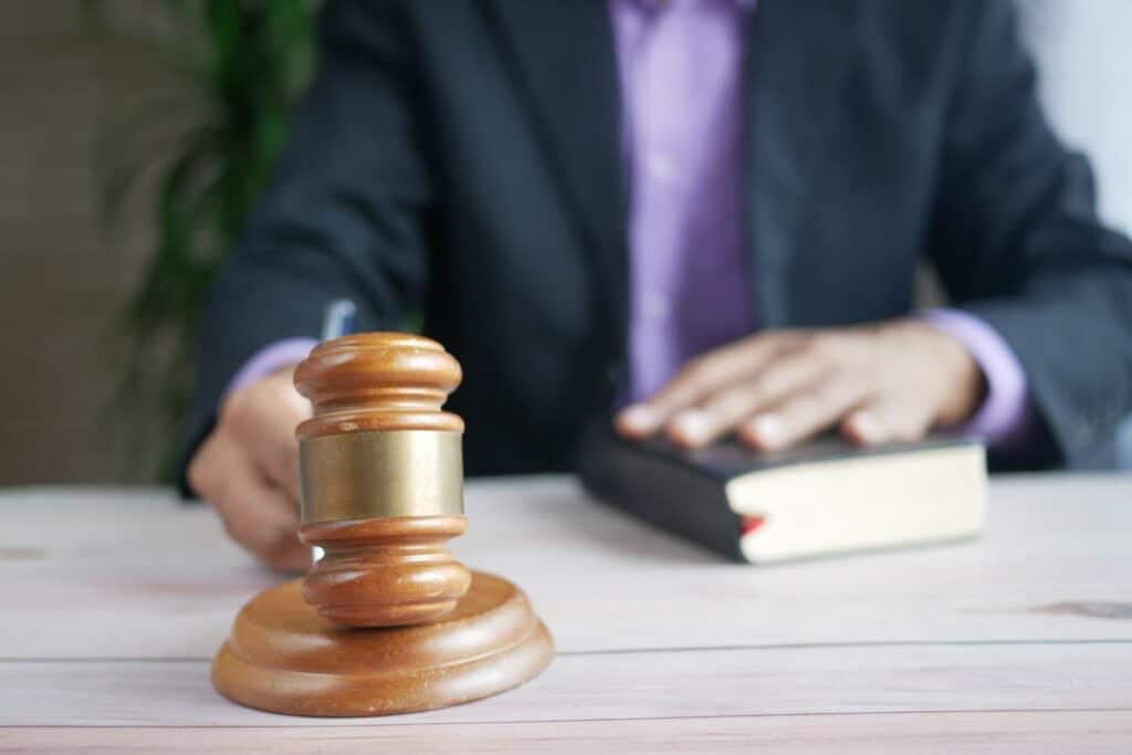 Close-up of a judge's gavel with a person in a suit holding a book, symbolizing the legal implications of the Renters' Reform Bill and its impact on the UK rental market