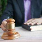 Close-up of a judge's gavel with a person in a suit holding a book, symbolizing the legal implications of the Renters' Reform Bill and its impact on the UK rental market