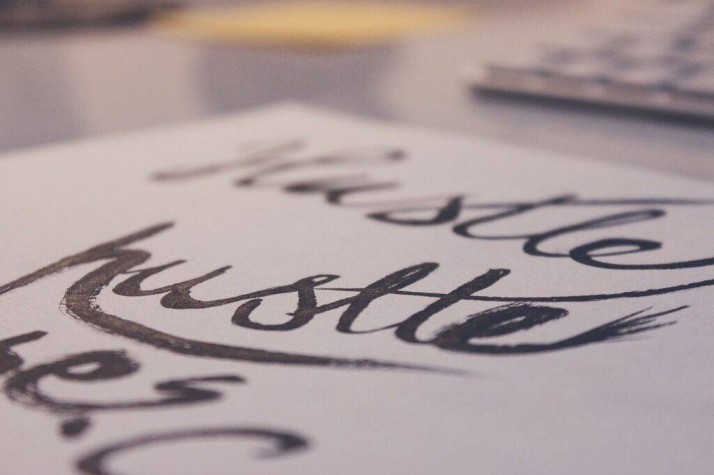 Close-up of the word "hustle" written in cursive, representing the comparison between side hustles and part-time jobs