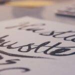 Close-up of the word "hustle" written in cursive, representing the comparison between side hustles and part-time jobs