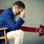 Man stressed by debt with a downward arrow, symbolizing financial crisis