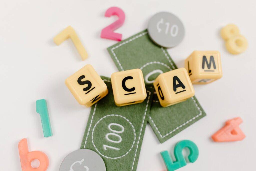 Blocks spelling 'SCAM' with numbers and play money, symbolizing technology's role in both facilitating and combating scams