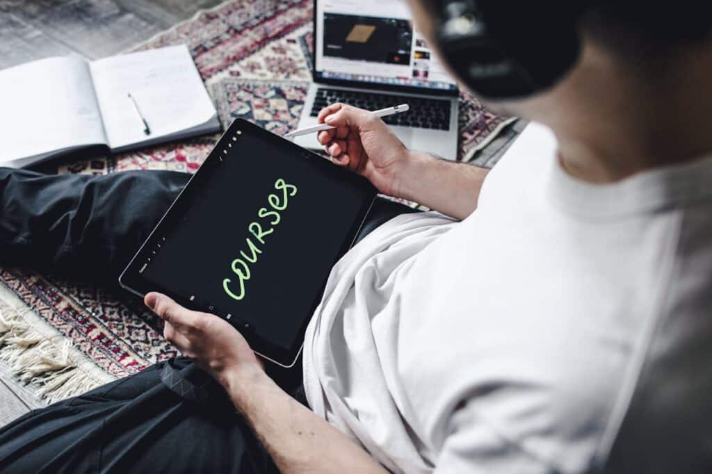 Person using a tablet with the word "Courses" on the screen, representing online learning through top universities and business schools on Coursera