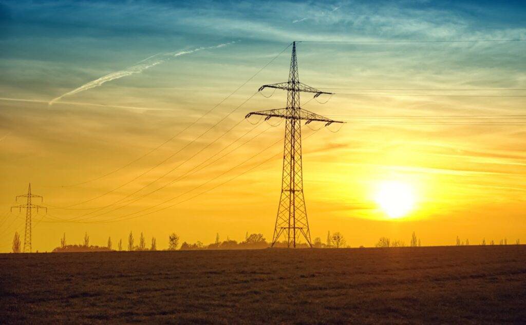 Sunset over power lines, symbolizing the journey of UK energy prices, trends, and the energy cap over the last 5 years