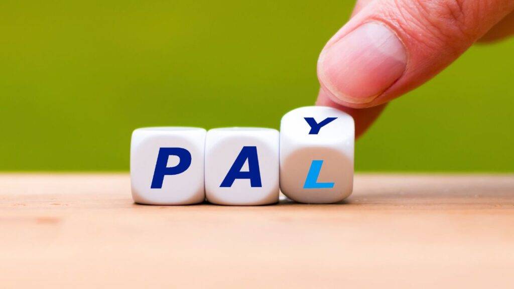 Hand adjusting dice to spell "PAY," symbolizing expert strategies to unlock the full potential of PayPal for maximum benefits