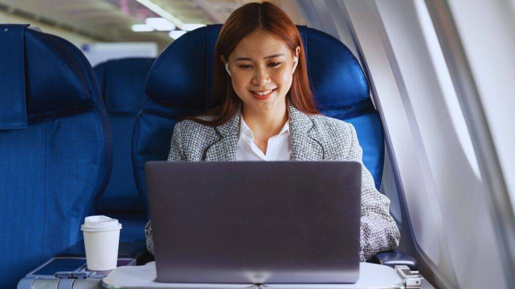 A woman working on a laptop in an airplane seat, illustrating in-flight WiFi service on American Airlines