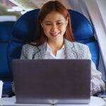 A woman working on a laptop in an airplane seat, illustrating in-flight WiFi service on American Airlines