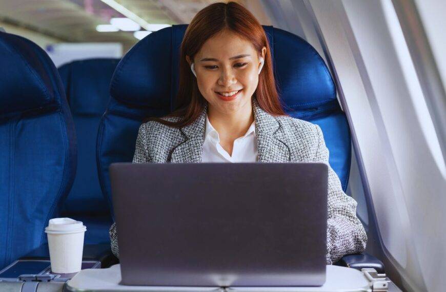 A woman working on a laptop in an airplane seat, illustrating in-flight WiFi service on American Airlines