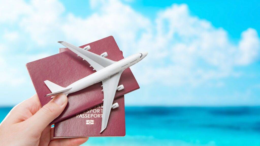 A hand holding passports and a toy airplane against a blue sky, symbolizing travel rewards and maximizing Avios points value