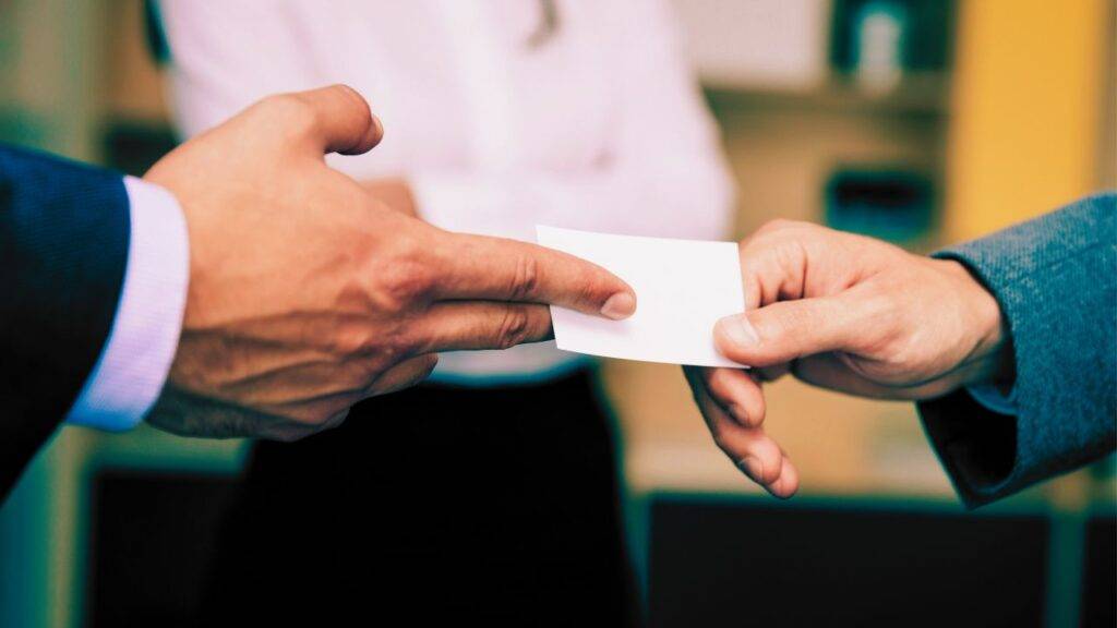 Close-up of a business card exchange, highlighting modern technologies like QR codes and NFC