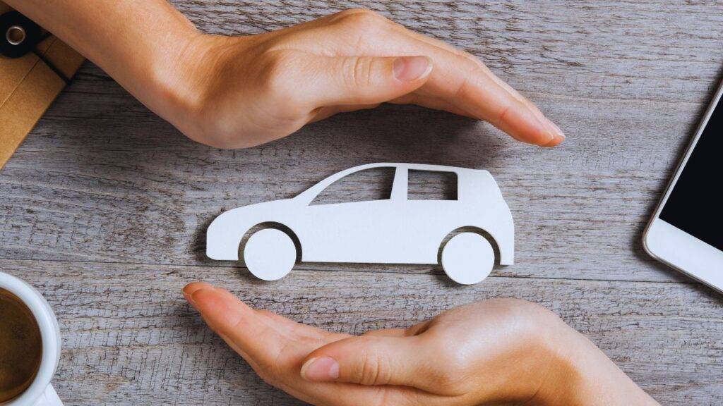 Hands protecting a car model representing car insurance and premium variations