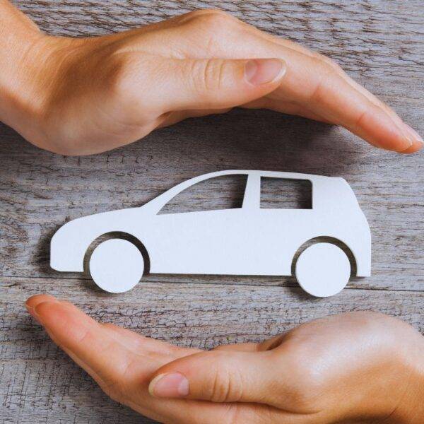 Hands protecting a car model representing car insurance and premium variations