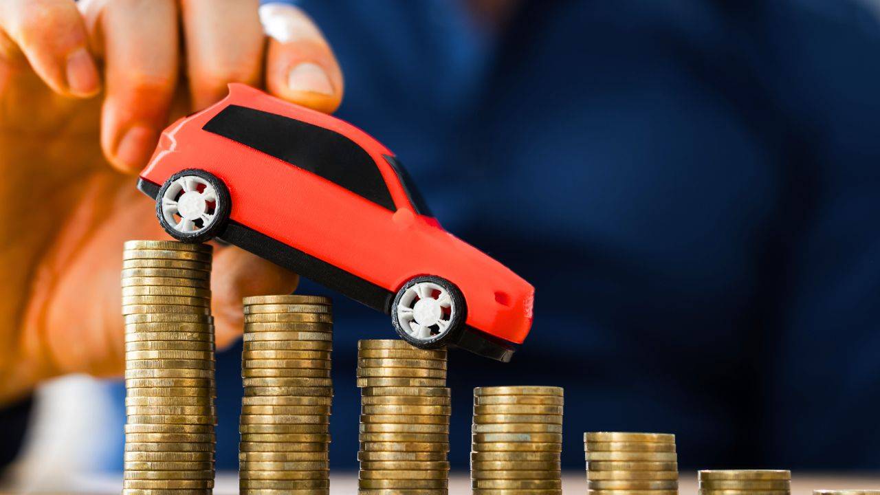 Toy car placed on stacked coins, representing gap insurance and vehicle value in case of theft