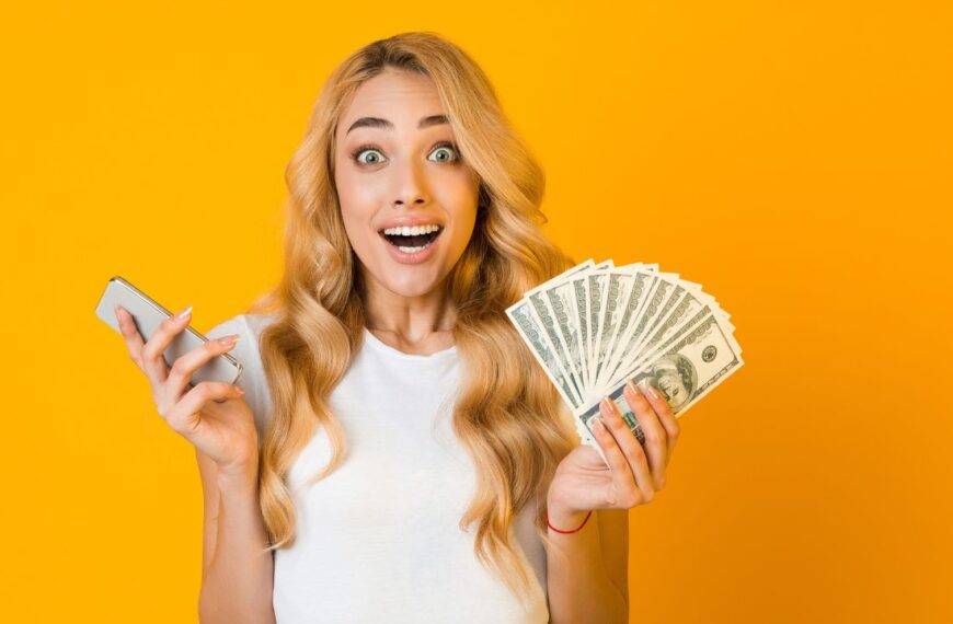 Excited woman holding cash and a phone, representing ways to make money online for beginners