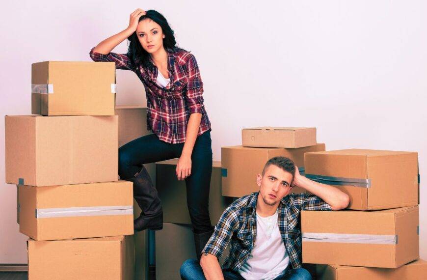 frustrated couple sitting among moving boxes, symbolizing the stress of relocation and the need for financial assistance.