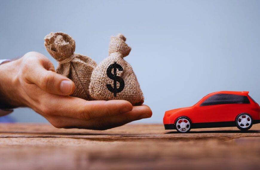 A hand holding money bags next to a red toy car, symbolizing car loan pre-approval.