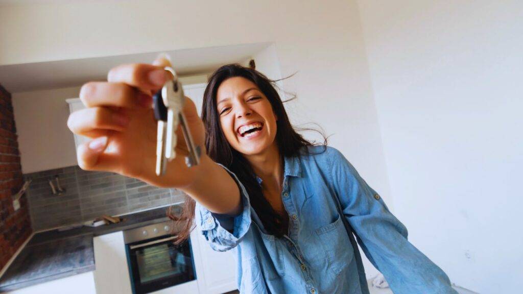 A happy woman holding keys in a new home, representing the concept of shared ownership in the UK