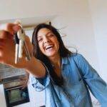 A happy woman holding keys in a new home, representing the concept of shared ownership in the UK