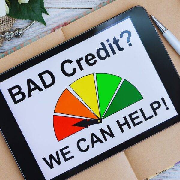 Tablet displaying a credit score gauge with the text "Bad Credit? We Can Help!" on a desk, representing credit improvement tools.