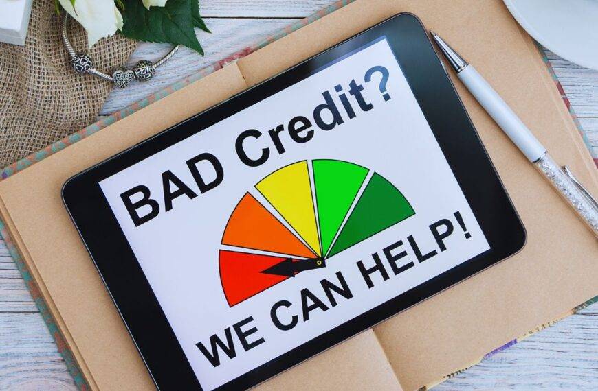 Tablet displaying a credit score gauge with the text "Bad Credit? We Can Help!" on a desk, representing credit improvement tools.