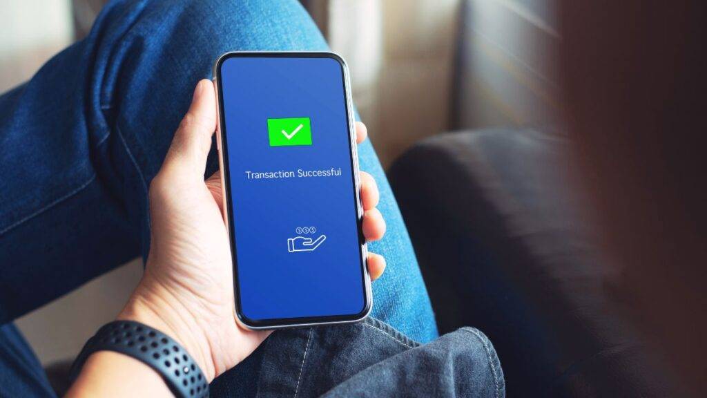 A person holding a smartphone displaying a "Transaction Successful" message, symbolizing mobile banking services